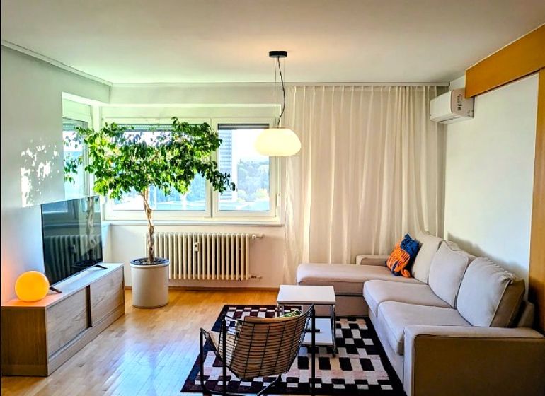 Living room in a 4-room apartment with a corner sofa and a floor with a wooden decor.