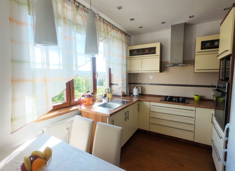 A kitchen in a 2-room apartment with a wooden decor floor and light curtains.