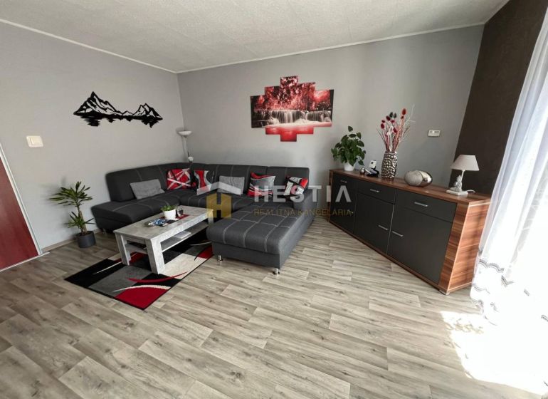 Living room in a three-room apartment with a wooden decor floor and a gray sofa.