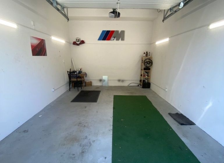 In the garages, there is a green carpet, a shelf, and a decoration with a logo on the wall.