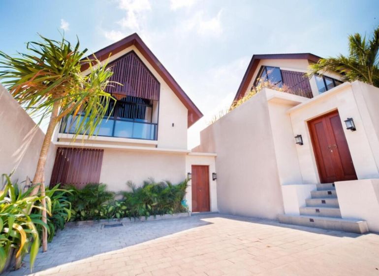 Villa in Bali with a garden and palm trees, modern architecture, stone pathway.