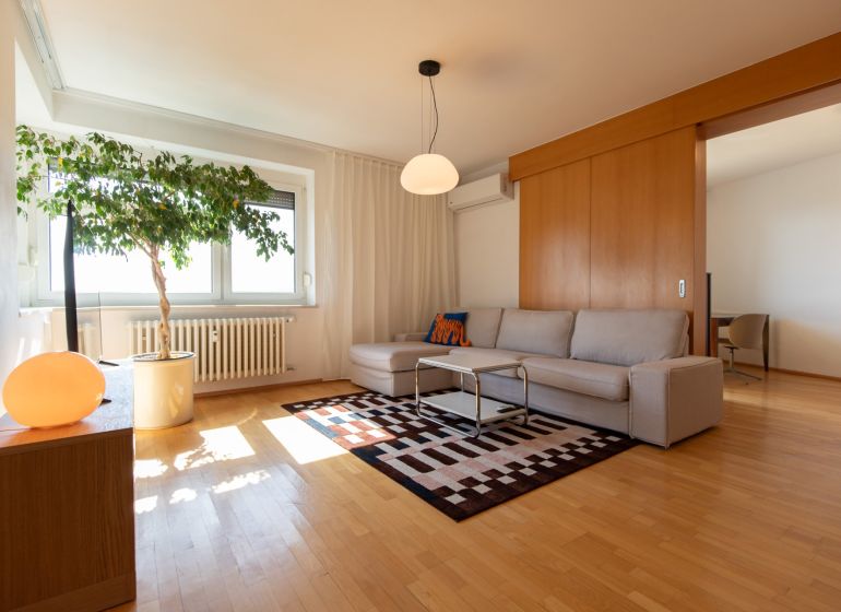 Living room in a 4-room apartment with a sofa, carpet, and wood-patterned flooring.
