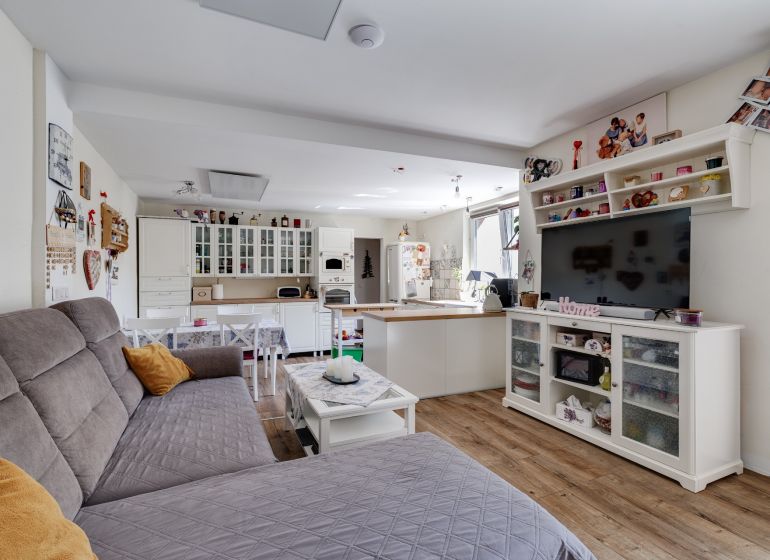 Living room in a family house with wood-patterned flooring, white furniture, and a sofa.