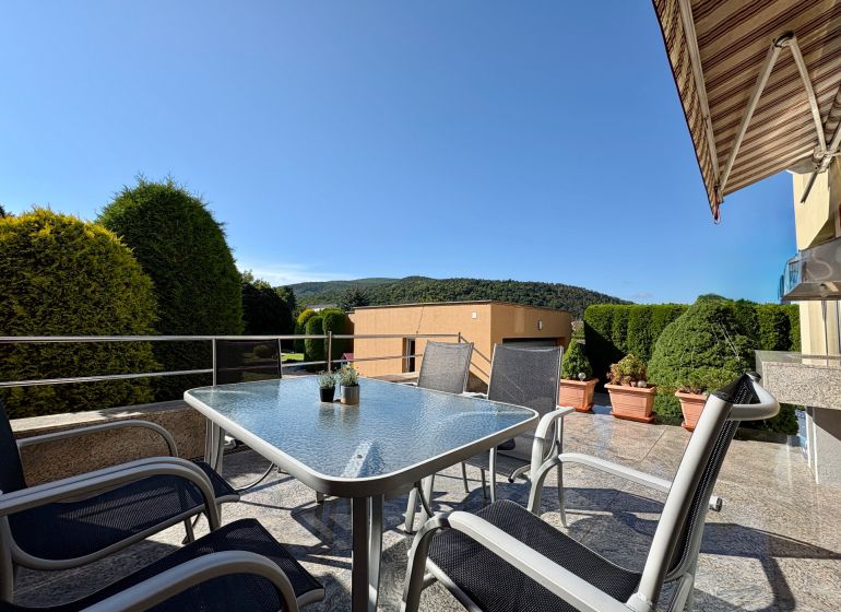 In Partizánske, a terrace of a family house with garden furniture and a view of greenery.