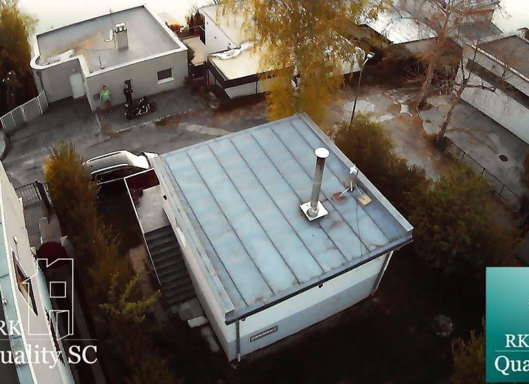 Cottage in Senec at SUNNY LAKES SOUTH, with a flat roof, surrounding trees, and a road.