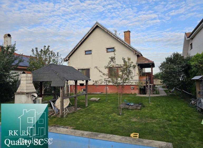 A family house in Turany with a lawn, a gazebo, and an outdoor fireplace in the garden.