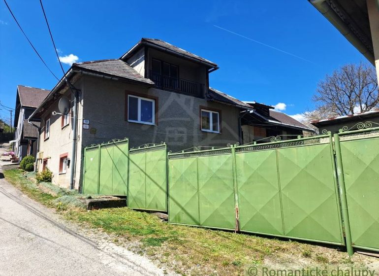 A family house in Heľpa with a large green gate on a sunny street.