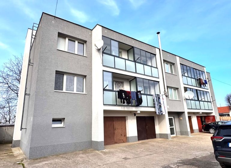 A three-story apartment building with balconies and cars in Hlboké.