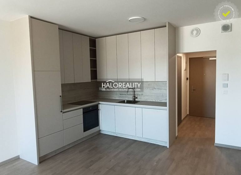A kitchen in light shades with a wood-patterned floor in a studio apartment.