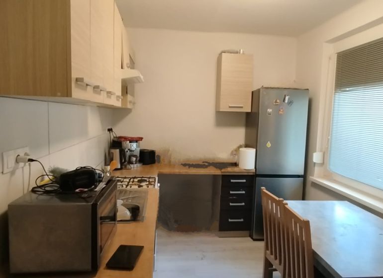 Kitchen in a 2-room apartment with appliances, a dining table, and large windows.