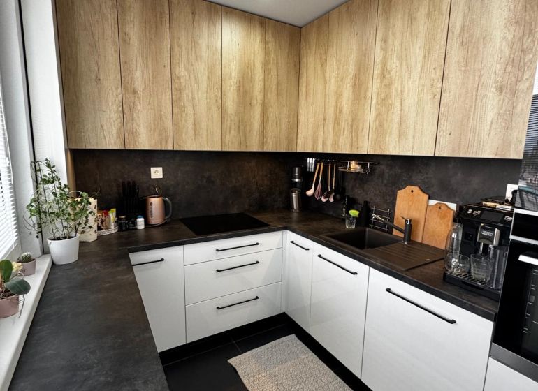 A kitchen with white cabinets and wooden decor in a 3-room apartment.