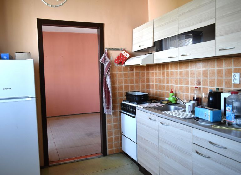 A kitchen in a 3-room apartment with tiled walls and a wooden decor floor.