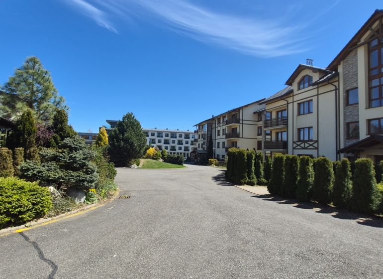 The greenery around the recreational apartments in Stará Lesná in the High Tatras under the blue sky.