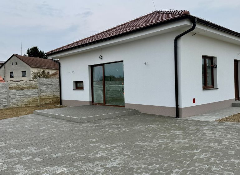 A family house on Hlavná Street in Vlčany with a white facade and a paved courtyard.