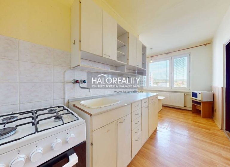 A kitchen in a 2-room apartment with a gas stove and a wooden decor floor.