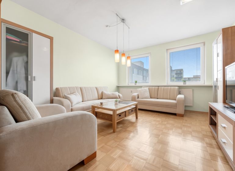 Living room in a 3-room apartment with a sectional sofa and a floor with a wood decor.