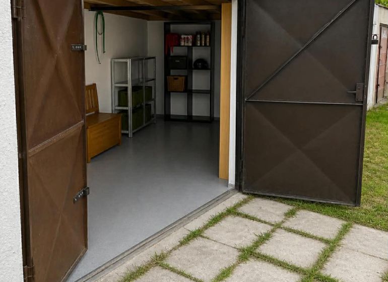 Open garages in Nové Zámky with shelves and a concrete walkway.