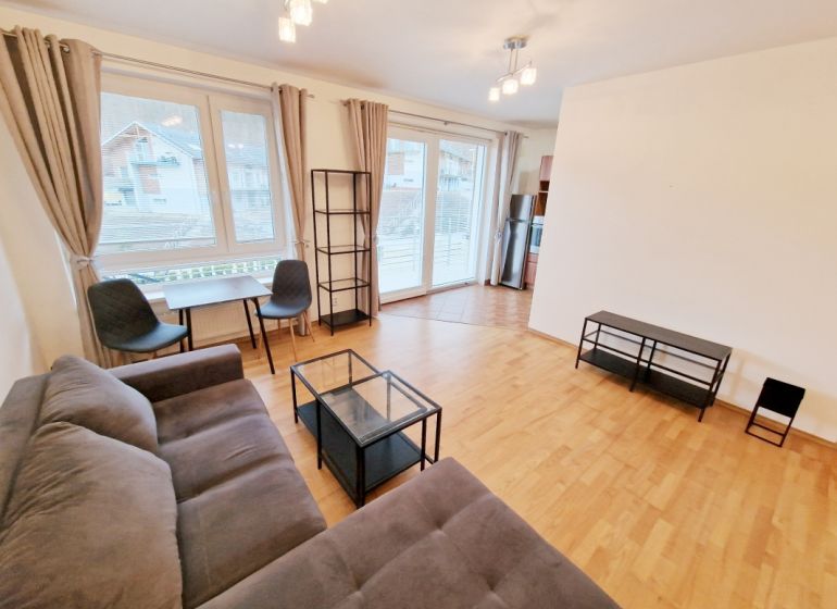A bright living room with a sofa, a table, and a wooden decor floor in a 3-room apartment.