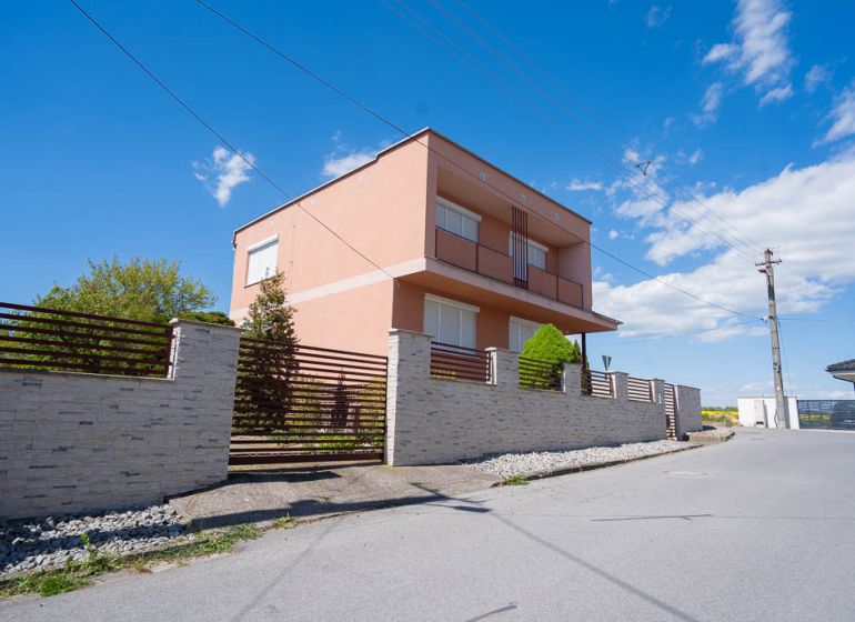 A family house on B. Tablica Street in Dudince with a stone fence and blue sky.