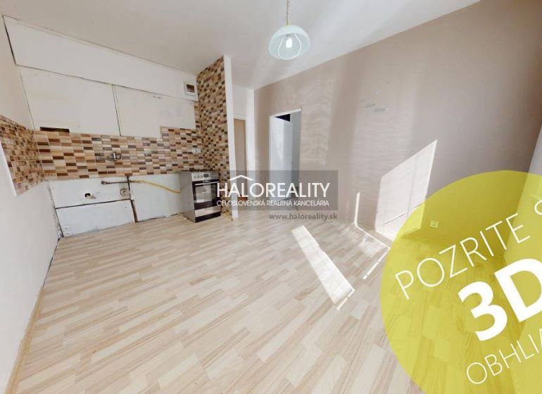 A room with a wooden decor floor and a kitchenette in a studio apartment.
