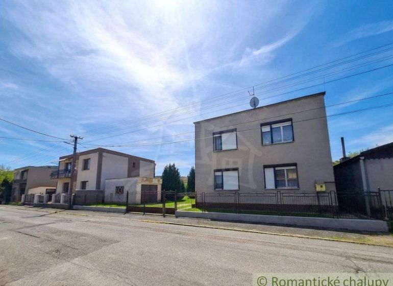 Family houses in Mýtna near a street with a clear sky and a fence.