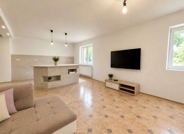 Living room in a family house with a TV, sofa, and tiles.