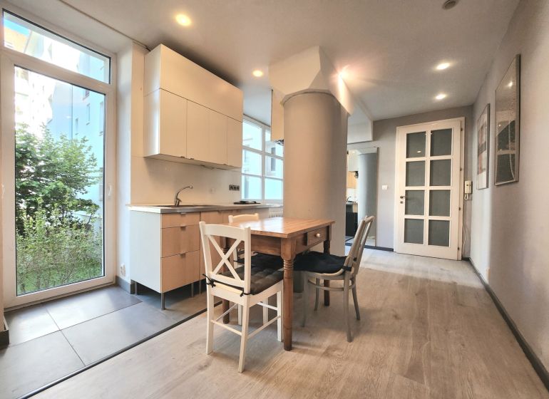 A kitchen in a 2-room apartment with a wooden table and a floor with a wooden decor.