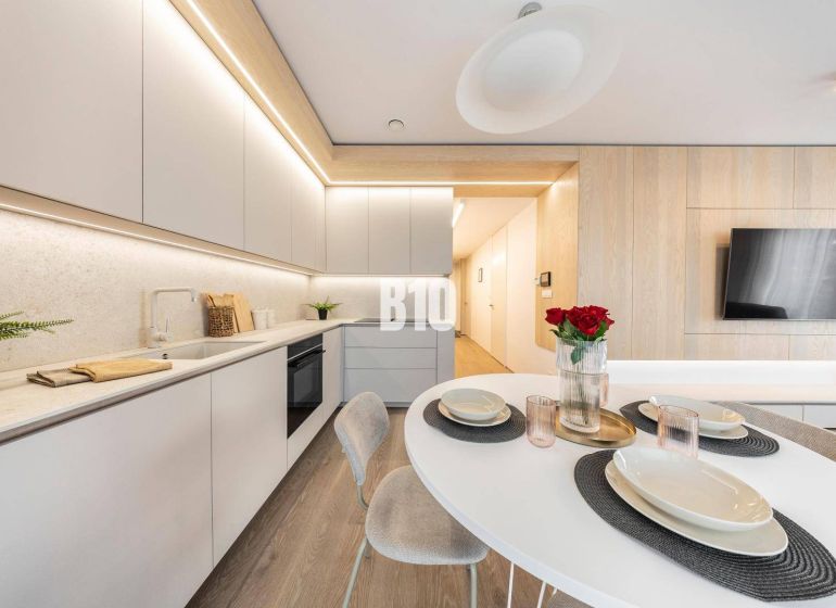 Stylish kitchen in a 3-room apartment with wood-patterned flooring and modern furniture.