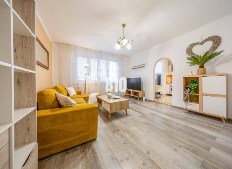 Living room in a two-room apartment with a yellow sofa and a wooden decor floor.