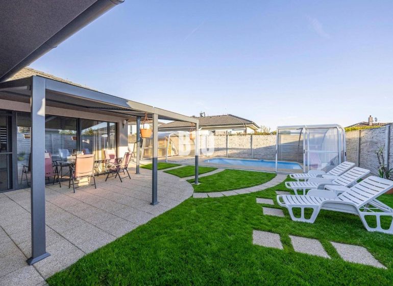 A family house in Most pri Bratislave with a terrace, a swimming pool, and sun loungers on the lawn.