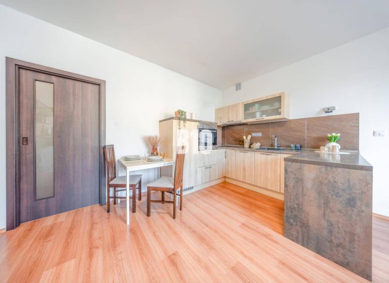 Kitchen corner in a 2-room apartment with a wooden decor floor and a dining table.