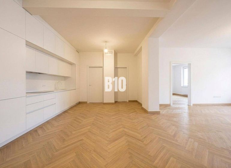 Interior of a 3-room apartment with a white kitchen and a floor with a wood decor.