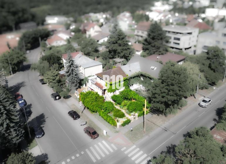 A family house in the Bratislava - Staré Mesto area, surrounded by greenery and a road with cars.