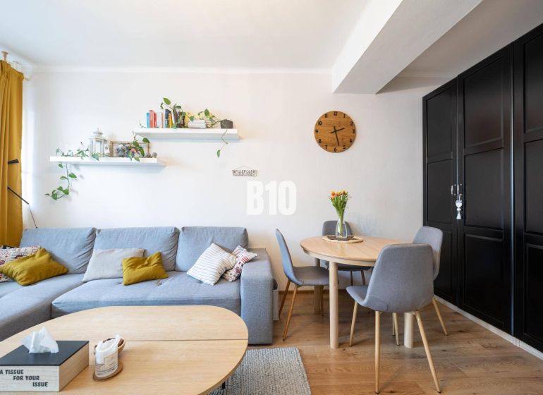 Living room with a gray sofa, round table, and wood-patterned flooring in a two-room apartment.