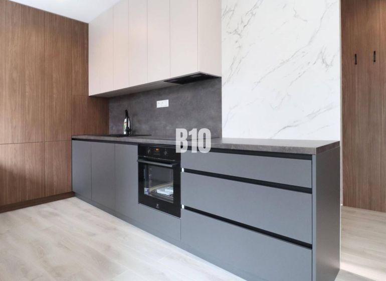 A kitchen in a 2-room apartment with a wooden decor floor and modern cabinets.