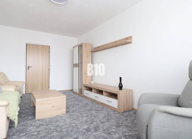 Living room with a beige sofa, gray armchair, and furniture with a wooden decor in a 3-room apartment.