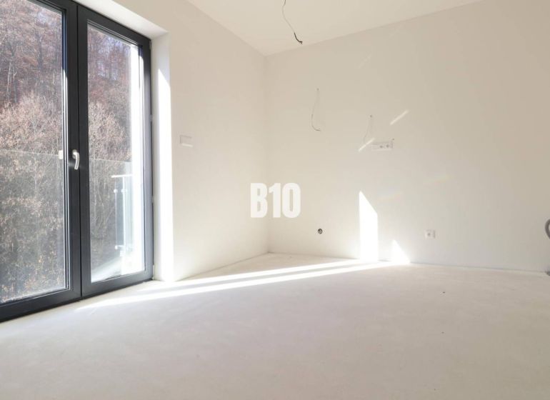 An empty room in a 3-room apartment with large windows and a view of nature.