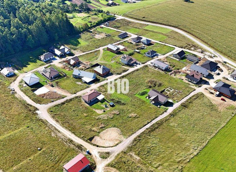 Aerial view of building plots in Necpaly surrounded by forests and agricultural landscape.