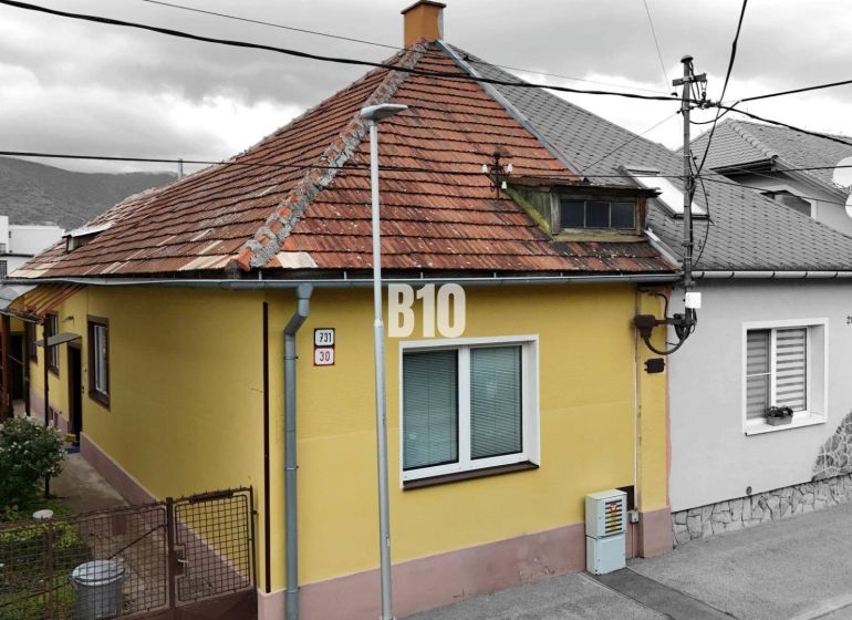 A family house in Martin with a yellow facade and a sloped roof, next to the access walkway.
