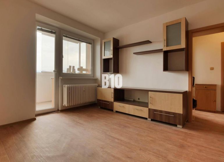 A room with furniture, a wooden decor floor, balcony doors.
