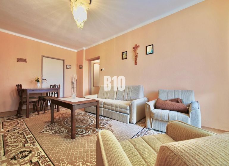 A living room in a three-room apartment with seating and a carpet, furnished in a classic style.