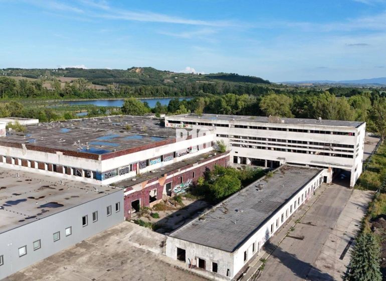 Production premises in Levice with abandoned buildings surrounded by nature and a body of water.