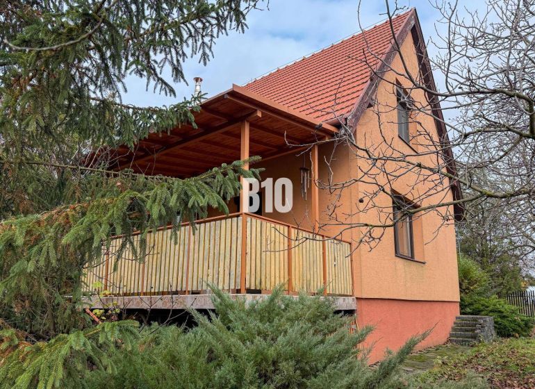A family house in Vlkas surrounded by greenery, traditionally sloped roof, wooden balcony.