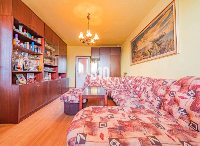 Living room in a 3-room apartment with a wooden decor floor and a corner sofa.