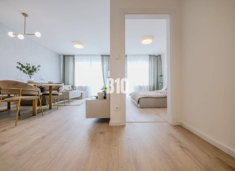 Interior of a 2-room apartment with a wooden decor floor, dining table, and bed.