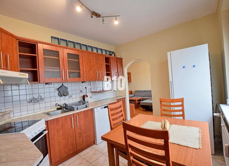 The kitchen of a 3-room apartment with wooden decor cabinets and a dining table.