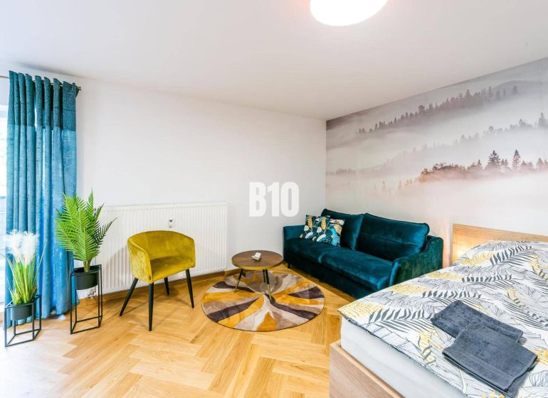 1-bedroom apartment with a wooden decor floor, a sofa, and a nature-themed photo wallpaper.