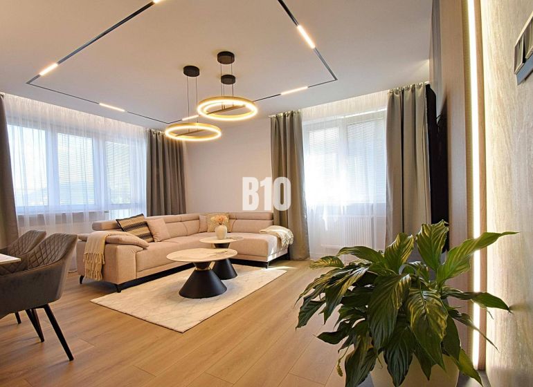 Living room in a 3-room apartment with a wooden decor floor, a light couch, and a plant.