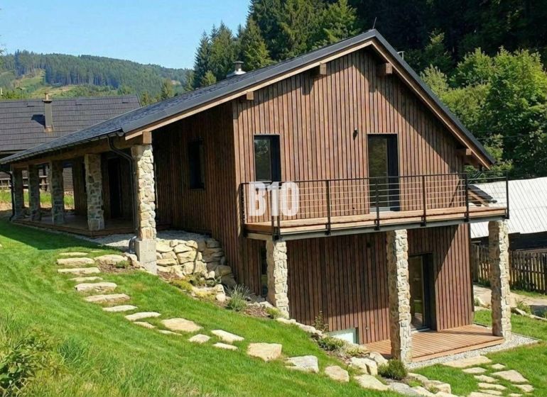 A wooden cottage in Horná Mariková surrounded by greenery and hilly landscape.
