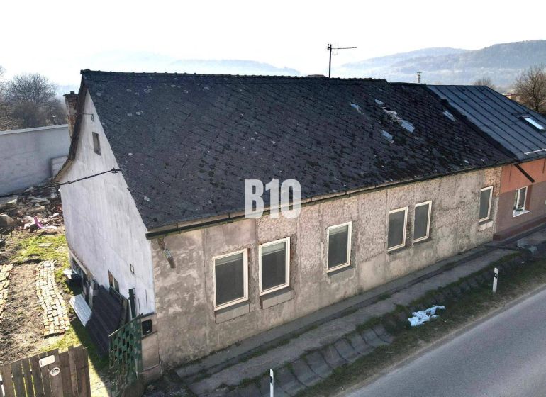 A family house in Bytča with a worn-out roof and plaster, next to the main road.